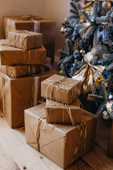 Closeup of wrapped gifts in kraft paper under a christmas tree.