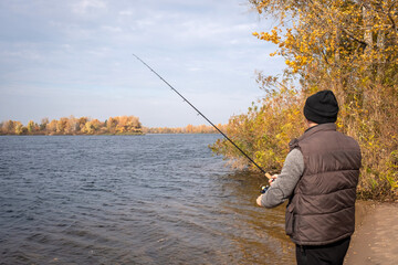 A fisherman with spinning rods in his hands is fishing on the bay.