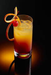 Cocktail tequila sunrise on a black reflective background.