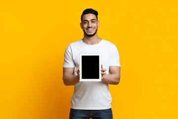 Cheerful arab guy showing digital tablet with blank screen
