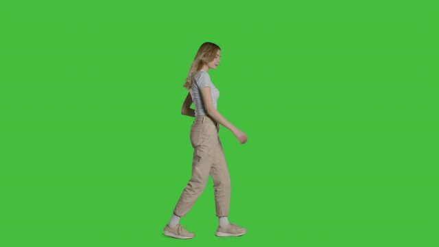 Casual young blonde woman walking. Shot on a mock-up green screen in the background. 4k uhd video on Chroma key