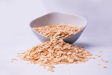 Healthy breakfast. Dry rolled oatmeal in bowl isolated on white background. Top view. Oat flakes in bowl isolated with clipping path. Concept of healthy lifestyle, healthy eating, dieting, sport.