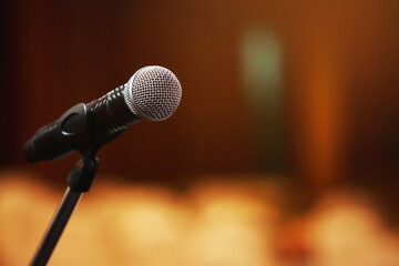 Close up of microphone on stage lighting at concert hall or conference room. copy space banner. soft focus.