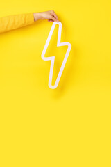 hand holding lightning bolt icon over yellow background