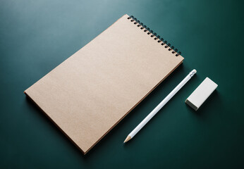 Photo of blank kraft sketchbook, pencil and eraser on green background. Branding identity template.