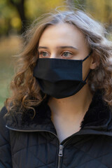 The girl observes the mask regime while walking in the park