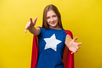 Young Russian woman isolated on yellow background in superhero costume and doing coming gesture
