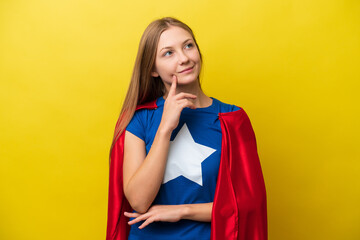 Young Russian woman isolated on yellow background in superhero costume and thinking