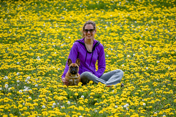 Latin woman with dog in flower field in spring.