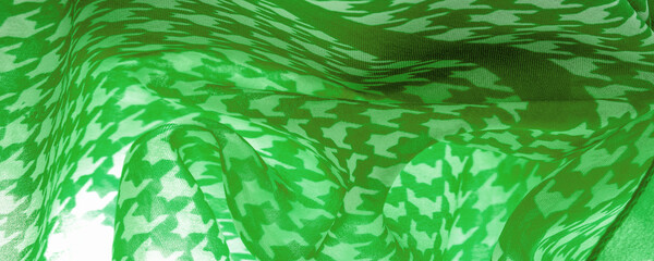 Fototapeta na wymiar Delicate green silk chiffon in vibrant colors with geometric print. Surprisingly light, smooth, sandy to the touch fabric. One of the most elite types