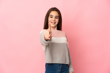 Little girl isolated on pink background showing and lifting a finger