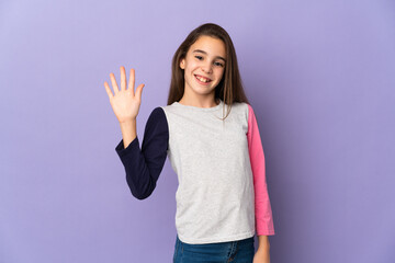 Little girl isolated on purple background saluting with hand with happy expression © luismolinero