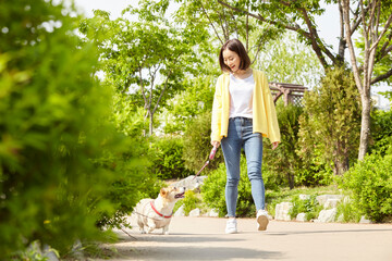 Young woman with her pet dog walking in the park