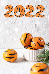 Tangerines with painted stripes. The concept for the tiger new year with a Christmas tree. Tiger mandarines