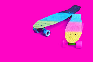 Two neon rainbow colored Penny board skateboards isolated on solid bright crimson background....