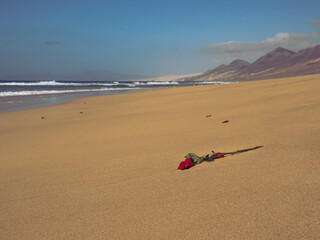 Playa desierta con montañas y una rosa en el suelo