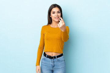 Young caucasian woman isolated on blue background doing coming gesture