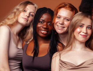 Obraz premium young pretty african and caucasian women posing cheerful together on brown background, lifestyle diverse nationality people concept