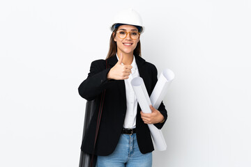 Young architect caucasian woman with helmet and holding blueprints over isolated background giving a thumbs up gesture