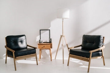 Leather armchairs standing near side table and lamp in office