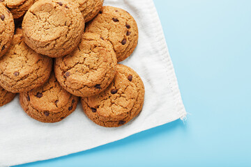 A bunch of oatmeal cookies with chocolate on a napkin on a blue background