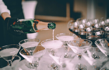 waiter pouring champagne wine from bottle in glasses