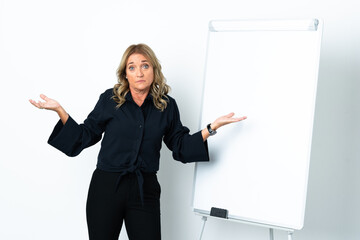 Middle aged blonde woman over isolated white background giving a presentation on white board