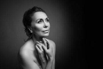 Fototapeta premium Portrait of a sensual fifty year old woman on grey studio background. Monochrome shot.