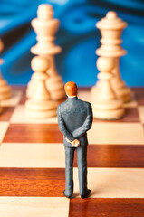 businessman figurine standing on a chessboard, business strategy concept