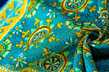 turquoise silk fabric with yellow drawings of flowers circles. Charmeuse has a beautiful drapery. This can be assembled in soft completeness. Texture