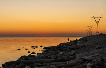 Orange sunset on the shore along the power line.