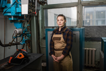 Fototapeta na wymiar Welder in overalls standing near welding machine and protective mask in factory