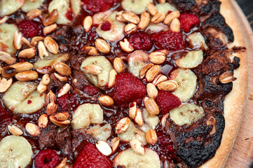 Sweet pizza with chocolate and fruits on black background