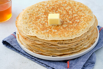 Crepes, thin pancakes with honey and butter on a white plate. Close up.