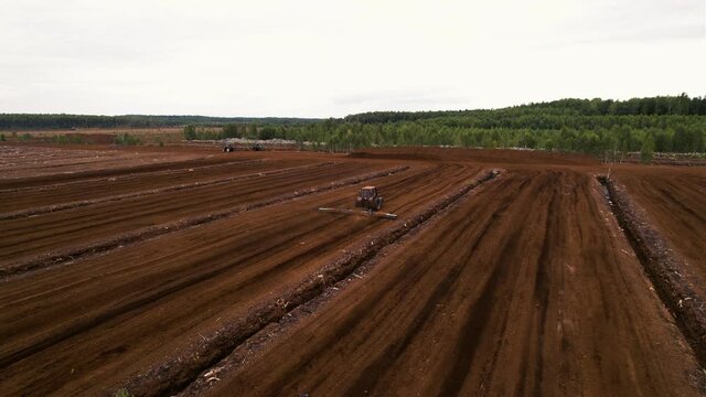 Peat Harvester Tractor on Collecting Extracting Peat. Mining and harvesting peatland. Area drained of the mire are used for peat extraction. Drainage and destruction of peat bogs.