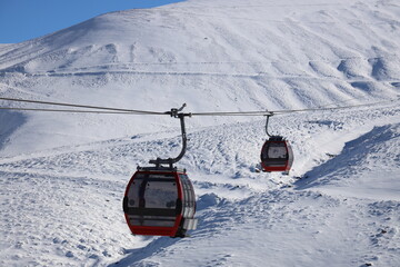 Fototapeta na wymiar Two empty ski lifts are moving on different directions in a snowy mountain