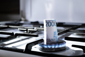 Concept of gas crisis. 2000 russian ruble bank note is burning on a kitchen stove. Cash money. High prices of natural resources. Blue flame. Utility debt. Energy war. Saving home budget. Close-up