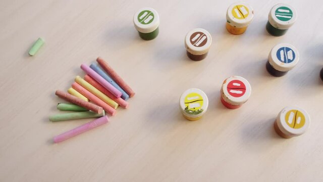 Kids art school. Painting tools. Creative staff. Colorful boxes with paint and chalks on white table indoor.