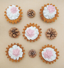 New Year card. Cupcake with white and pink cream on a parchment background. Craft paper forest cones on the background.