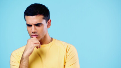 pensive young man in yellow t-shirt thinking isolated on blue.