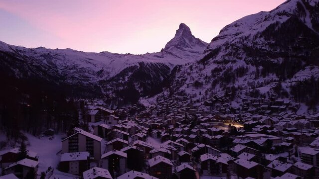Aerial drone footage of the sunset over the famous Zermatt village with the Matterhorn peak in winter in the alps in Switzerland. 