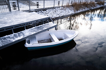 Small boat in the center of the lake of a snow-covered park