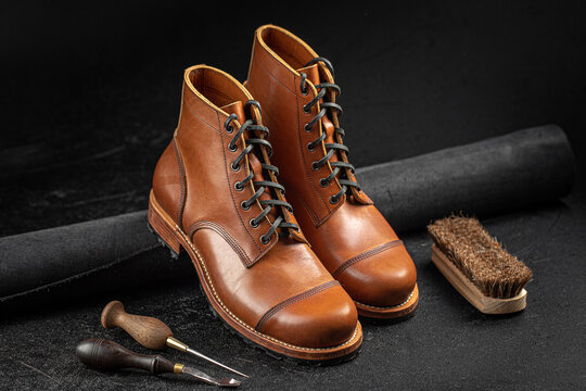 Handcrafted brown leather shoes with cobbler tools on the backgound