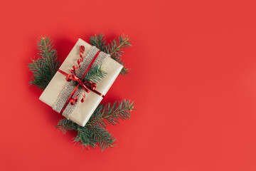 Craft gift box with spruce branch on a red background. Holiday concept.