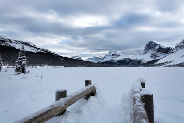 frozen Bow Lake in Jasper winter, bridge overlooking mountains and overcast sky