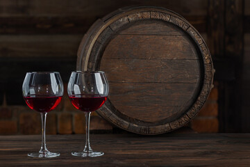Wine glasses with tall stem. Old oak barrel in a dark wine cellar at the winery. Aging cellaring wine tasting