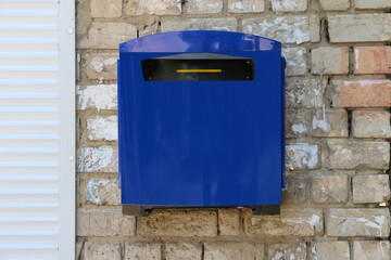 The mailbox is blue on an old brick wall