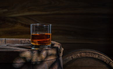 Glass decanter with cognac, brandy on a vintage background of a rustic oaken barrel. Alcoholic beverage. Still life in the old style