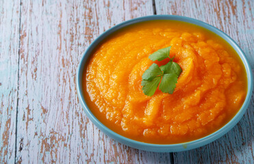 A bowl of pumpkin soup on a blue wooden table