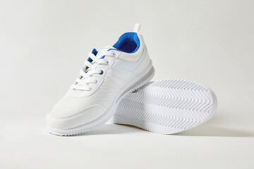 White sports sneakers with shoelace on a white wall background. Man sneakers for fitness. White...